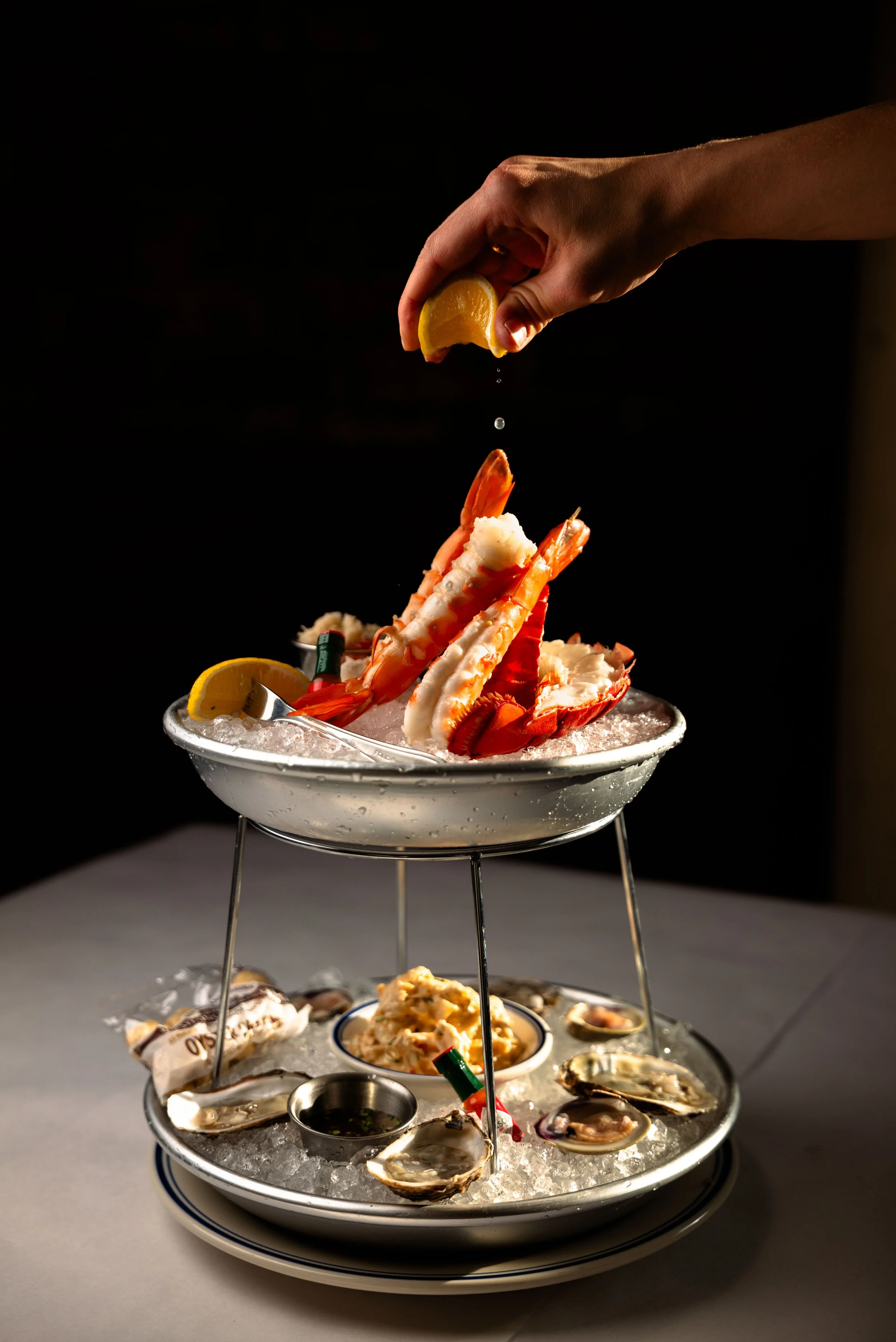 Seafood tower with a lemon being squeezed over crab