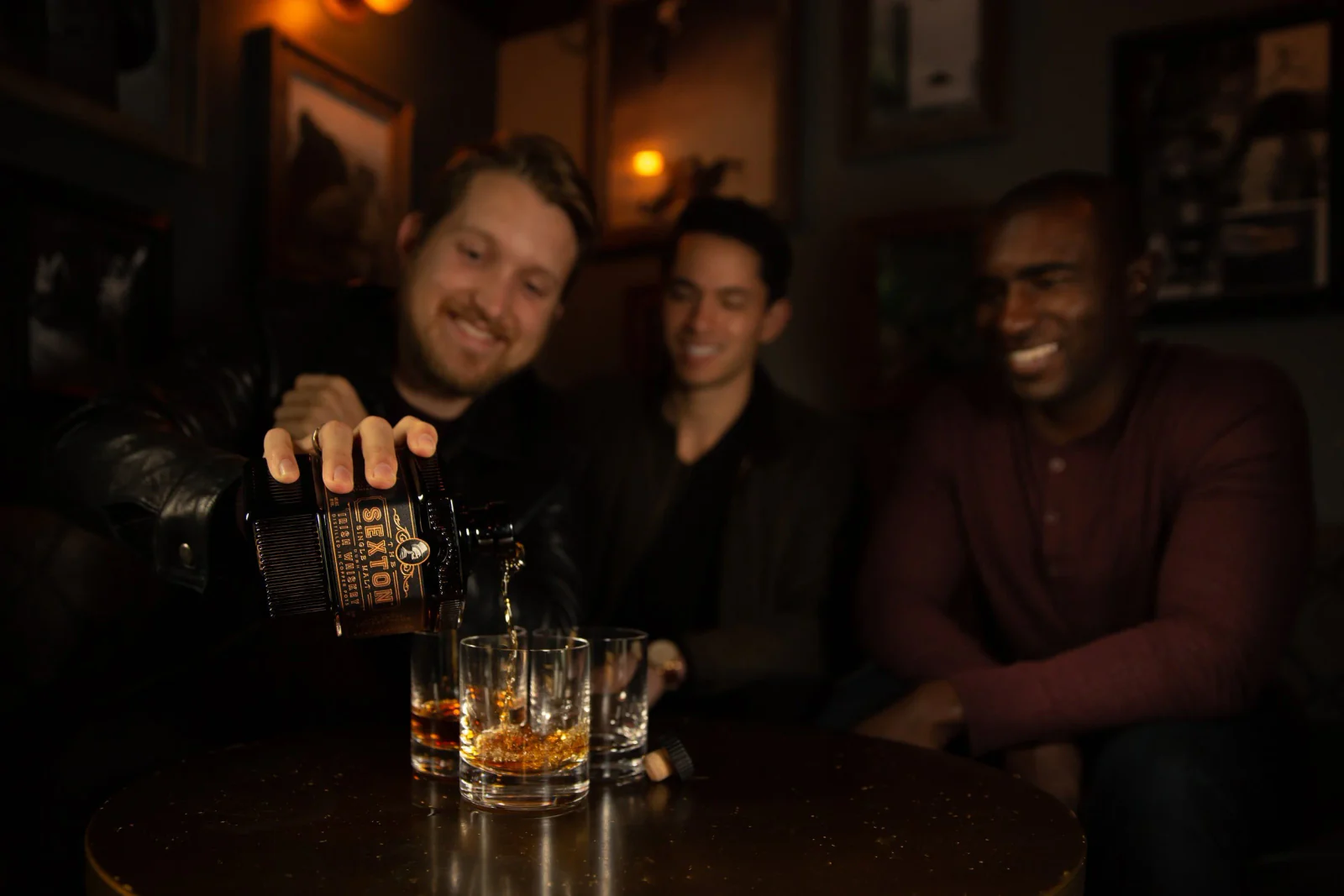 Friends around a pour of whiskey at the bar
